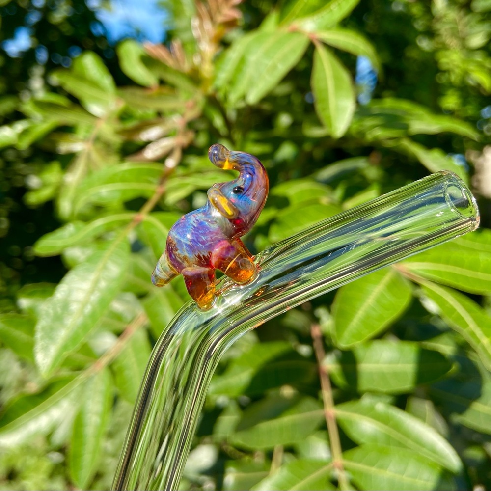 Reusable handmade glass straws with a figurine elephant glass on top .